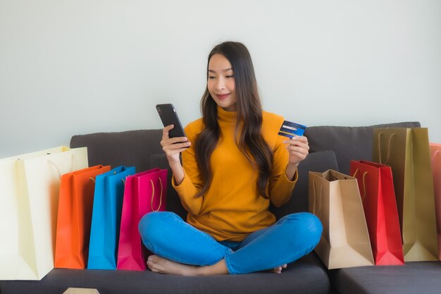Retrato joven mujer asiática con ordenador portátil con teléfono móvil inteligente y tarjeta de crédito para compras en línea