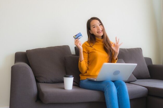 Retrato joven mujer asiática con ordenador portátil con teléfono móvil inteligente y tarjeta de crédito para compras en línea