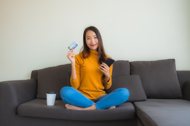 Retrato joven mujer asiática con ordenador portátil con teléfono móvil inteligente y tarjeta de crédito para compras en línea