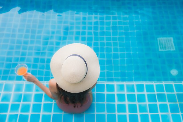 Retrato joven mujer asiática relajarse feliz sonrisa alrededor de la piscina en el hotel