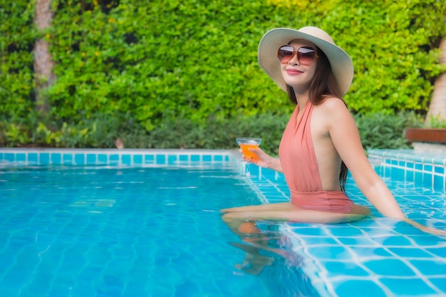 Retrato joven mujer asiática relajarse feliz sonrisa alrededor de la piscina en el hotel