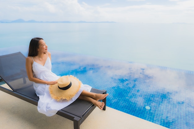 Retrato joven mujer asiática relajarse sonrisa feliz alrededor de la piscina en el hotel y resort