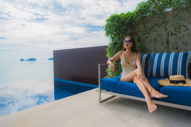 Retrato joven mujer asiática relajarse sonrisa feliz alrededor de la piscina en el hotel y resort