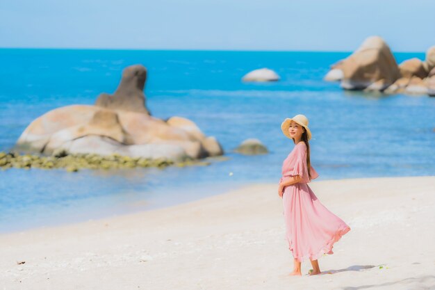 Retrato joven mujer asiática sonrisa feliz alrededor de la playa mar océano con palmera de coco para vacaciones