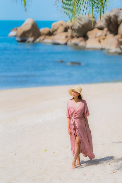 Retrato joven mujer asiática sonrisa feliz alrededor de la playa mar océano con palmera de coco para vacaciones