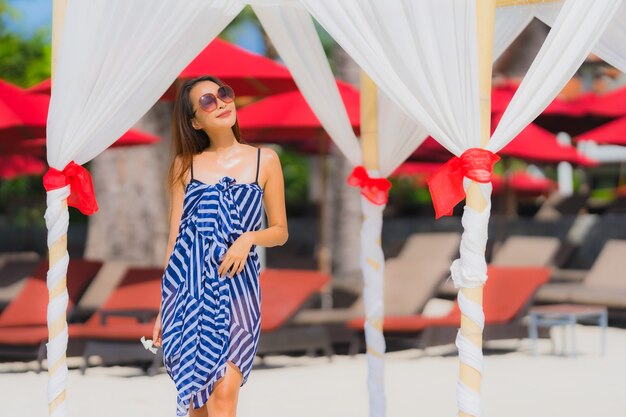 Retrato joven mujer asiática sonrisa feliz alrededor de la playa mar océano con palmera de coco para vacaciones