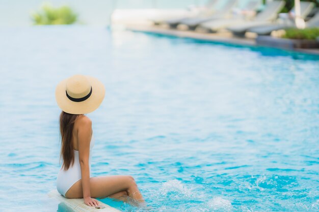 Retrato joven mujer asiática sonrisa feliz relajarse alrededor de la piscina en el hotel resort