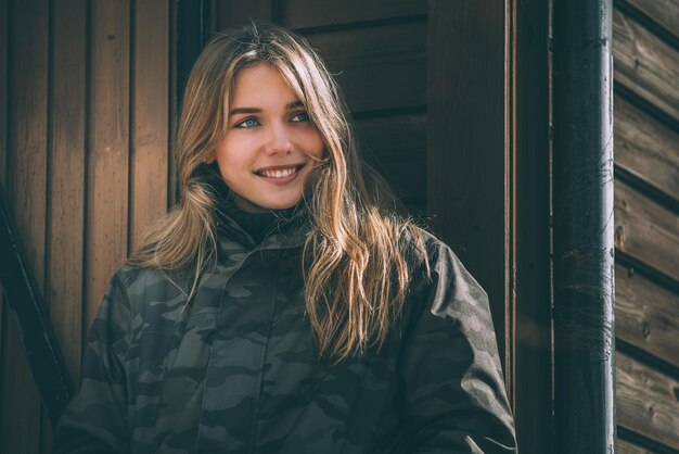 Retrato joven mujer bonita en invierno en una cabaña de troncos en la nieve.