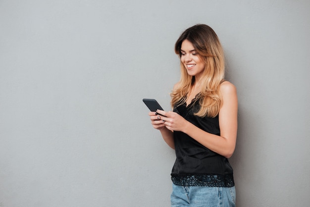 Foto gratuita retrato de una joven mujer casual mediante teléfono móvil