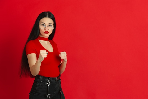 Retrato de joven mujer caucásica con brillantes emociones sobre fondo rojo studio