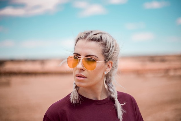 Retrato de una joven mujer caucásica con cabello con trenzas blancas y gafas de sol amarillas