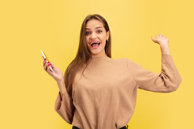 Retrato de joven mujer caucásica con emociones brillantes aisladas en amarillo