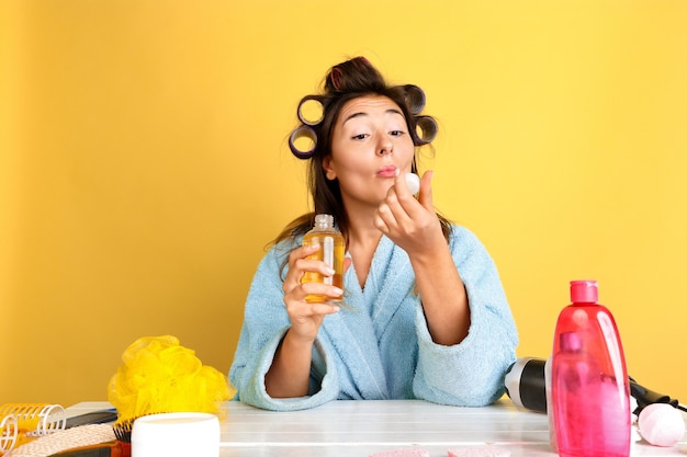 Retrato de joven mujer caucásica en su rutina de belleza día, piel y cuidado del cabello. Modelo de mujer con cosmética natural aplicando cremas y aceites de maquillaje. Cuidado corporal y facial, concepto de belleza natural.