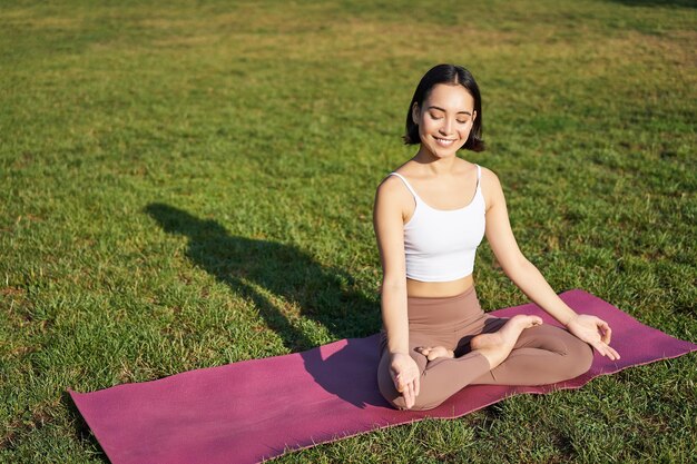 Retrato de una joven mujer consciente que practica yoga haciendo ejercicio inhalando y exhalando aire fresco en el parque sitt