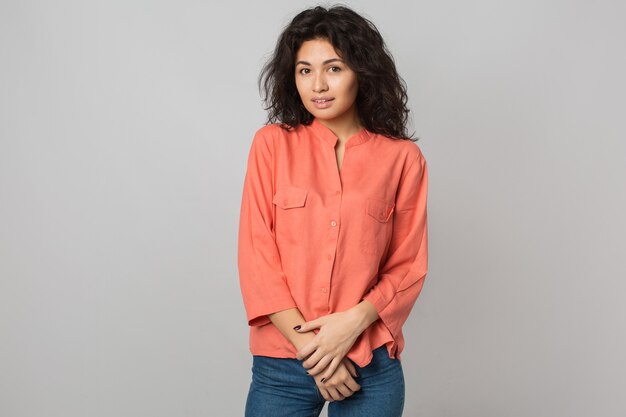 Retrato de joven mujer morena atractiva en camisa naranja