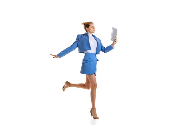 Retrato de una joven mujer de negocios con traje oficial azul brillante leyendo un proyecto y corriendo aislada sobre un fondo blanco