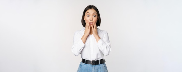 Retrato de una joven mujer de oficina sorprendida mujer de negocios asiática jadeando asombrada diciendo wow de pie impresionada por las noticias contra el fondo blanco