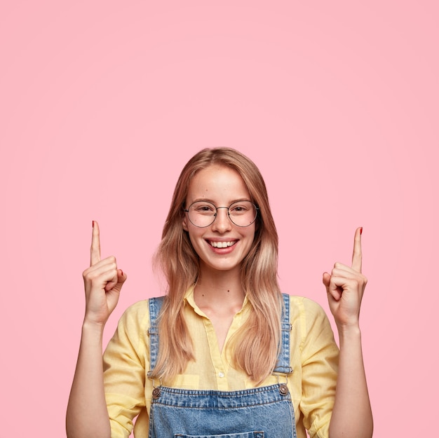 Retrato de joven mujer rubia en overoles de mezclilla