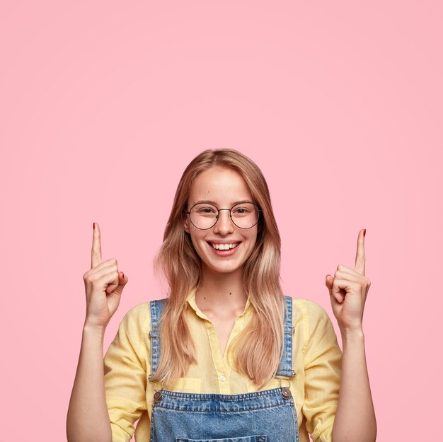 Retrato de joven mujer rubia en overoles de mezclilla