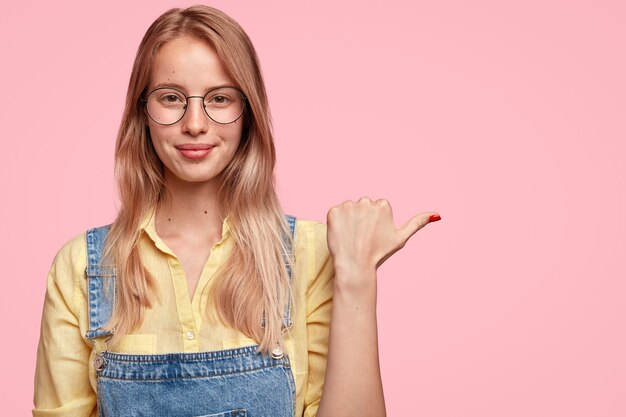 Retrato de joven mujer rubia en overoles de mezclilla