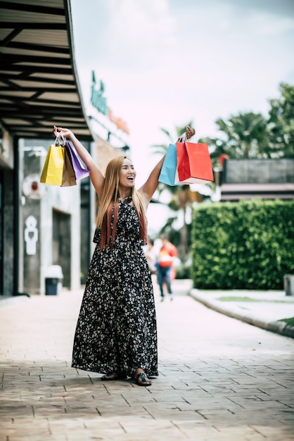 Retrato de joven mujer sonriente feliz con bolsas de compras caminando en la calle