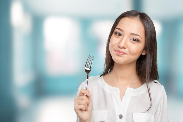 Retrato, de, joven, mujer sonriente, con, tenedor, en, ella, boca