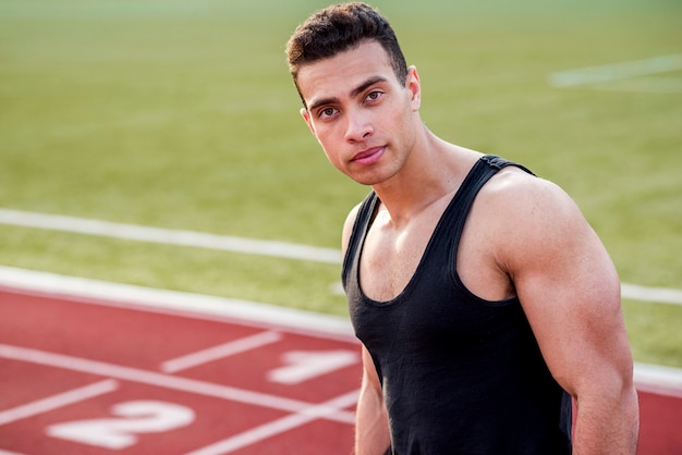 Retrato de joven musculoso en pista de carreras