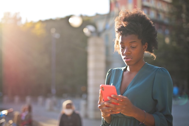 retrato de una joven negra hermosa mientras usa un teléfono inteligente