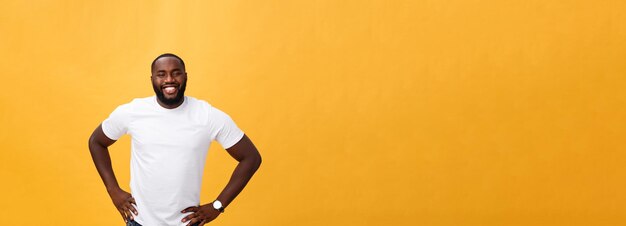 Retrato de un joven negro moderno sonriendo de pie sobre un fondo amarillo aislado