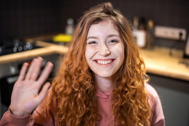 Retrato, de, joven, niña sonriente, con, jengibre, pelo, y, ondulación, mano