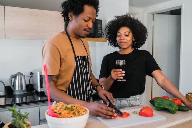 Retrato de joven pareja afro cocinando juntos en la cocina de casa. Concepto de relación, cocinero y estilo de vida.