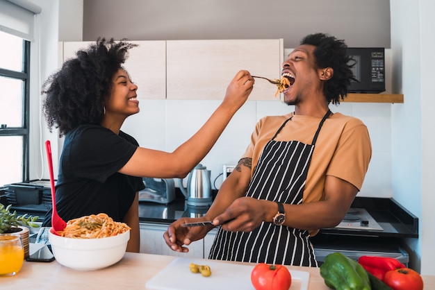 Retrato de joven pareja afro cocinando juntos en la cocina de casa. Concepto de relación, cocinero y estilo de vida.