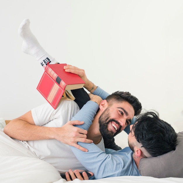 Retrato de la joven pareja amorosa en la cama contra la pared blanca