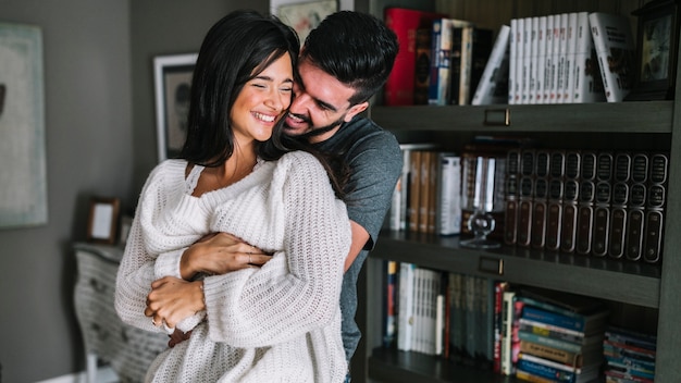 Retrato de la joven pareja cariñosa frente a la estantería