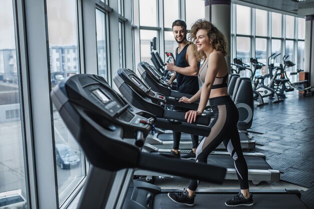 Retrato de joven pareja de deportes haciendo ejercicios de cardio en el gimnasio moderno