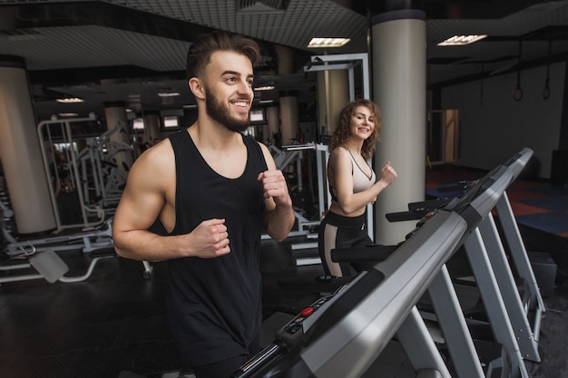 Retrato de joven pareja de deportes haciendo ejercicios de cardio en el gimnasio moderno