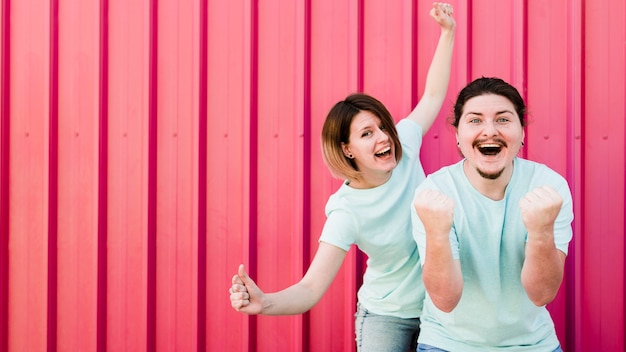 Retrato de joven pareja disfrutando con alegría contra el telón de fondo corrugado rojo