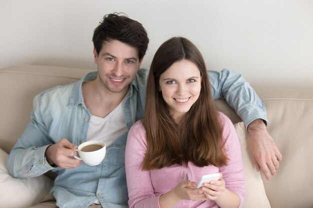 Retrato de joven pareja feliz, relajándose en el interior, disfrutando de café