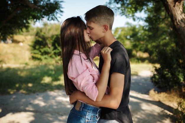 Retrato de una joven pareja hermosa abrazándose y besándose mientras están de pie en el parque