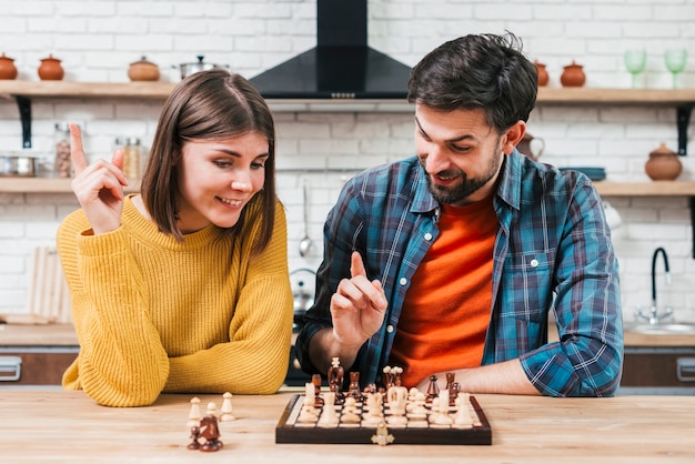 Retrato de una joven pareja jugando al ajedrez en la cocina