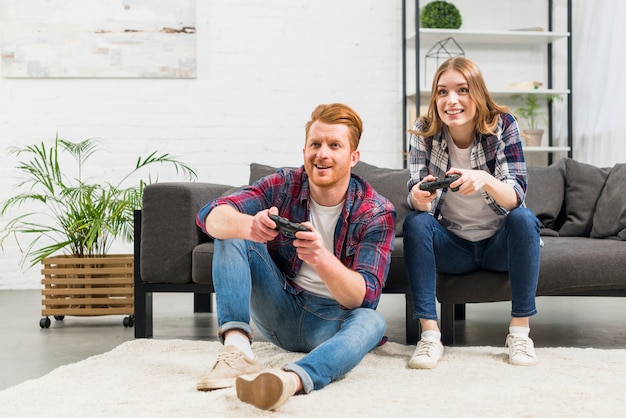 Retrato de joven pareja jugando el videojuego juntos en casa