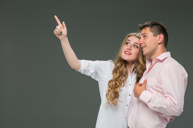 Retrato de una joven pareja de pie contra el fondo gris