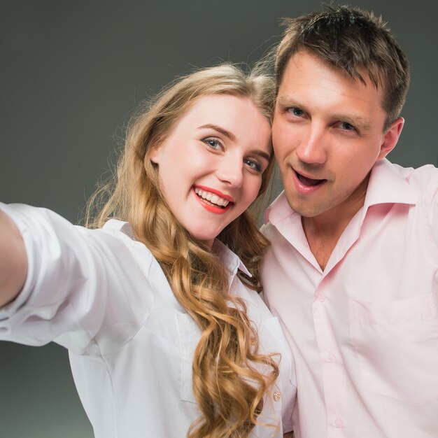 Retrato de una joven pareja de pie contra la pared gris