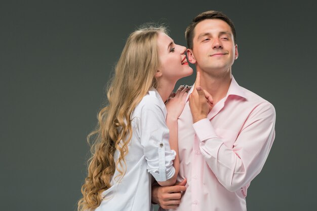 Retrato de una joven pareja de pie contra la pared gris