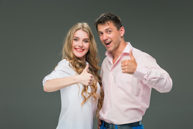 Retrato de una joven pareja de pie contra la pared gris