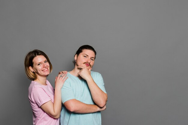 Retrato de una joven pareja de pie contra la pared gris