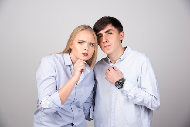 Retrato de una joven pareja posando en la pared gris.