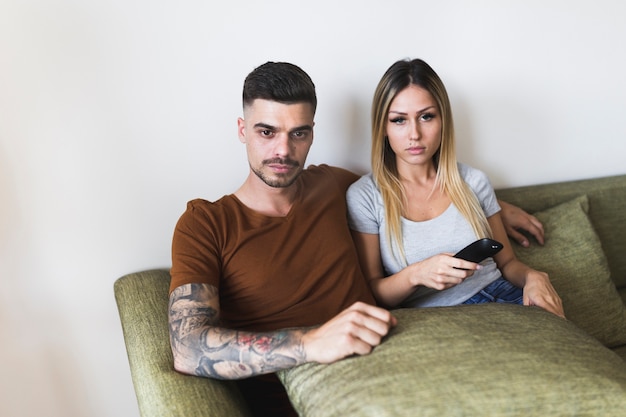 Foto gratuita retrato de la joven pareja sentada en el sofá viendo la televisión