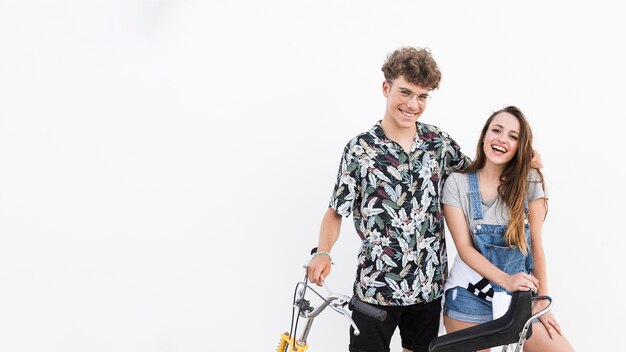 Retrato de una joven pareja sonriente con bicicleta sobre fondo blanco