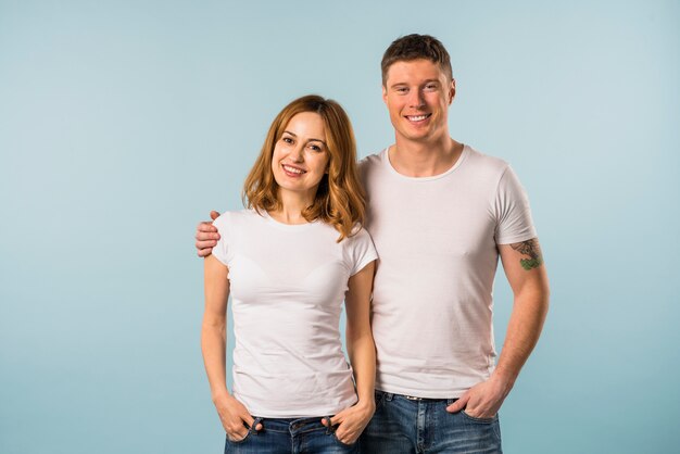 Retrato de una joven pareja sonriente contra el fondo azul